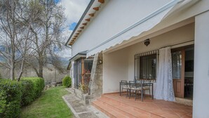 Una casa con patio, un muro de piedra y un jardín.