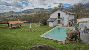 Una casa con piscina, terraza de madera y vistas a montañas.