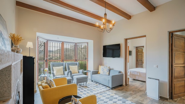 Una sala de estar con chimenea, sofá, sillón y televisión montada en la pared.