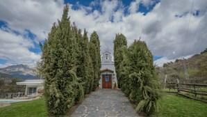 Un camino de piedra que conduce a un edificio con un campanario, rodeado de árboles de hoja perenne.