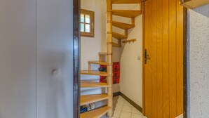 Un escalier en colimaçon en bois menant à une porte, une petite fenêtre et une boîte aux lettres rouge.