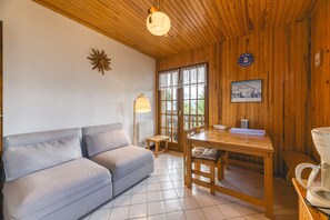 A cozy room with a wooden ceiling, a sofa, a dining table, and a coffee maker. - Apartment 'Meije 4 Chaleureux' with Mountain View, Balcony and Wi-Fi (Villard-Reculas)