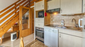 Una cocina con vigas de madera, microondas, horno, lavavajillas y un lavabo.
