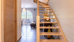 Un escalier en bois menant à un deuxième étage, une porte-fenêtre coulissante et une vue sur l’extérieur.