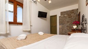 Una camera da letto con un letto, una televisione, un muro in pietra e una porta in legno.