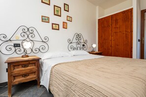 Une chambre à coucher avec un lit, une table de chevet, une lampe fixée au mur et une porte en bois.