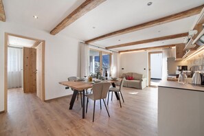 A spacious living area with a wooden dining table, chairs, and a sofa.
