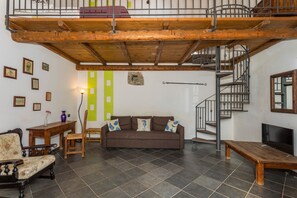 Una sala de estar con sofá, muebles de madera, una escalera y televisor.