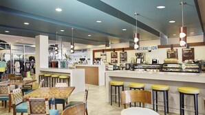 Un caffè moderno con un bancone centrale, sgabelli da bar e un'area salotto con tavoli e sedie.