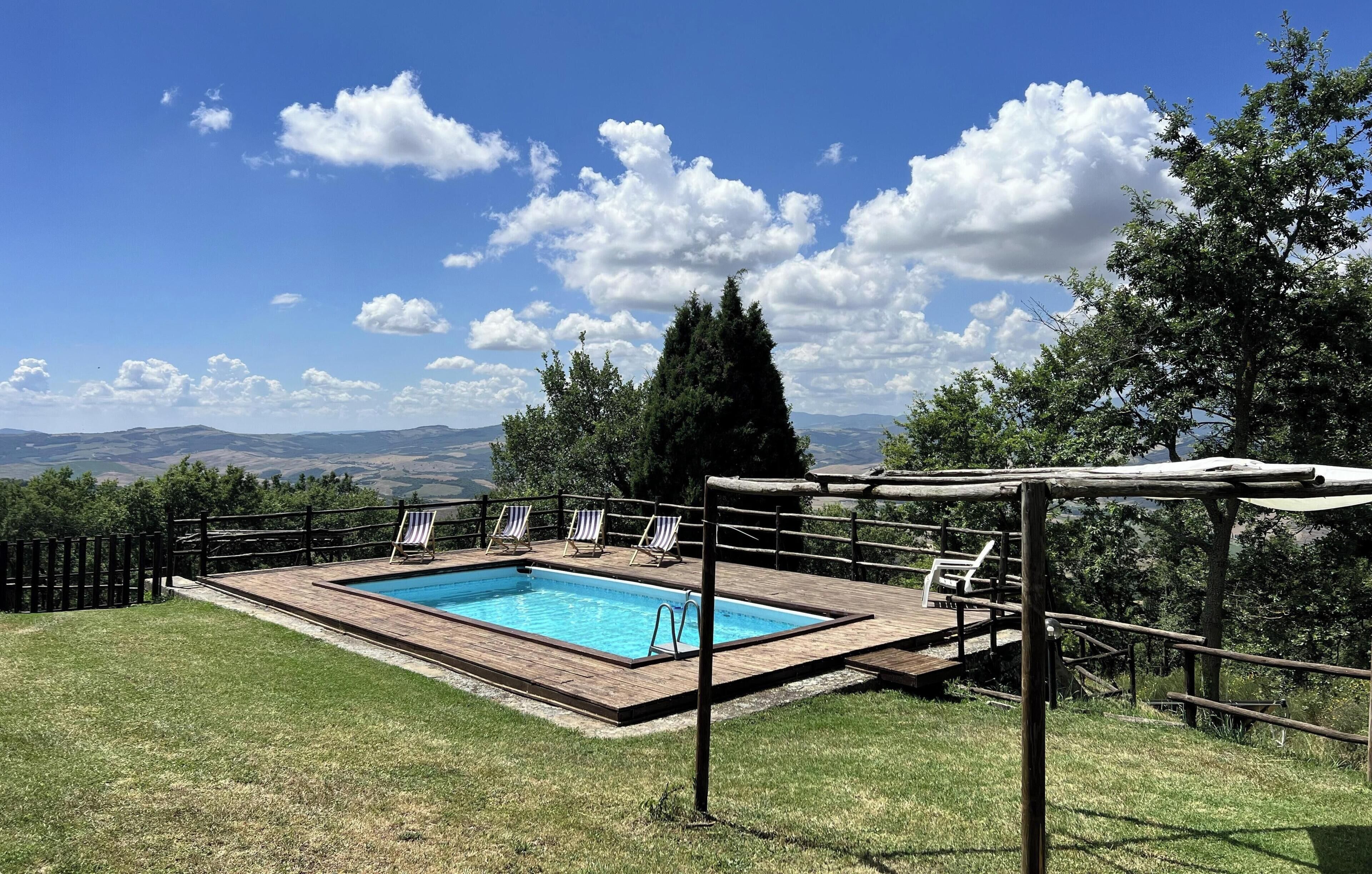 Ein rechteckiger Pool mit Holzterrasse, umgeben von einem Holzzaun und Liegestühlen.