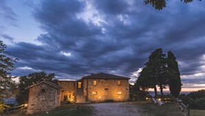 A stone building with a paved entrance, surrounded by trees and a gravel path. - 'L'uscio' Apartment with Mountain View, Shared Pool & Wi-Fi (Chianciano Terme)