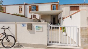 A residential building with a white exterior, numbered 222, a gated entrance, and a bicycle parked outside.