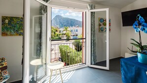 A room with a balcony, a table, a chair, and a potted plant.