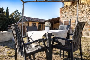 An outdoor seating area with wicker chairs and a table, set against a stone building with a tiled roof. - Room 'Girasole' with Mountain View and Wi-Fi (Chianciano Terme)