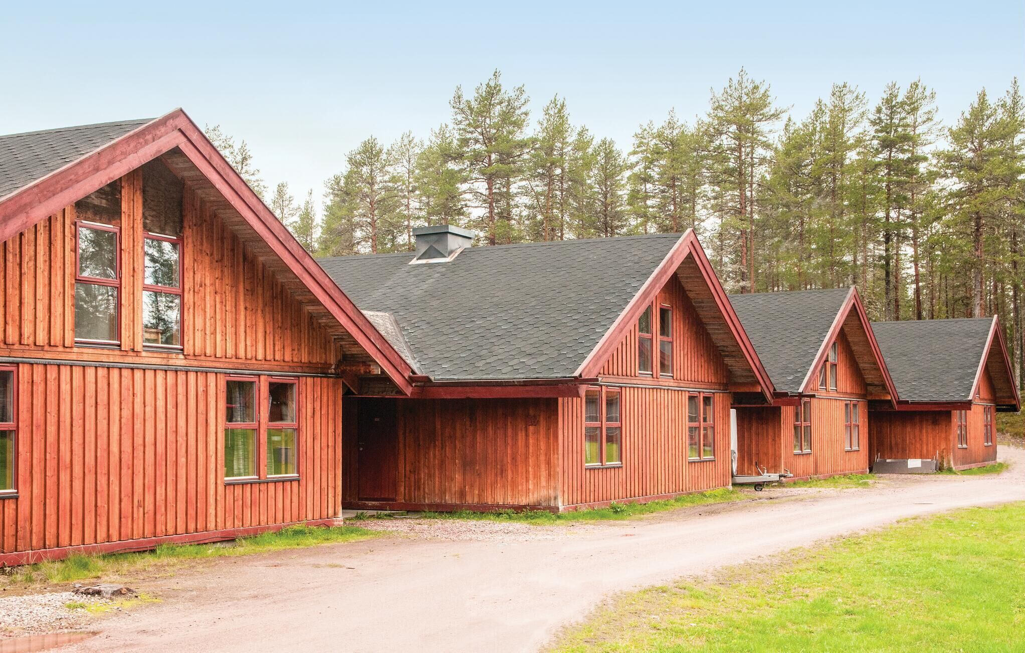 A row of wooden cabins with pitched roofs, set in a forested area.