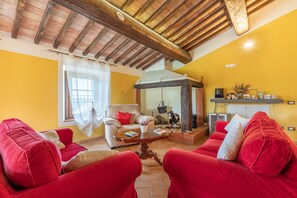 Un salon avec des canapés rouges, un plafond en bois, une cheminée et un mur jaune.