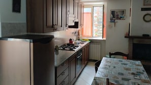 Una cocina con armarios de madera, estufa a gas y una ventana con cortinas.
