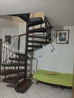 Escada em espiral com cama verde e um quadro na parede.