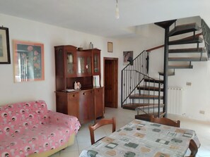 Ein Zimmer mit einer Couch, einem Tisch, einer Treppe und einem Schrank.