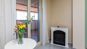 A room with a white table, a vase with flowers, a fireplace, and a sliding glass door leading to an outdoor area. - Apartment 'Etna Home' with Sea View, Wi-Fi and Air Conditioning (Santa Venerina)