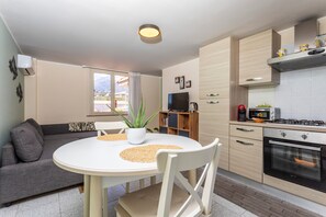 A modern kitchen with a dining area, a sofa, and a view of the outdoors.