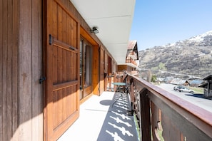Un balcone in legno con vista su una montagna e una strada.