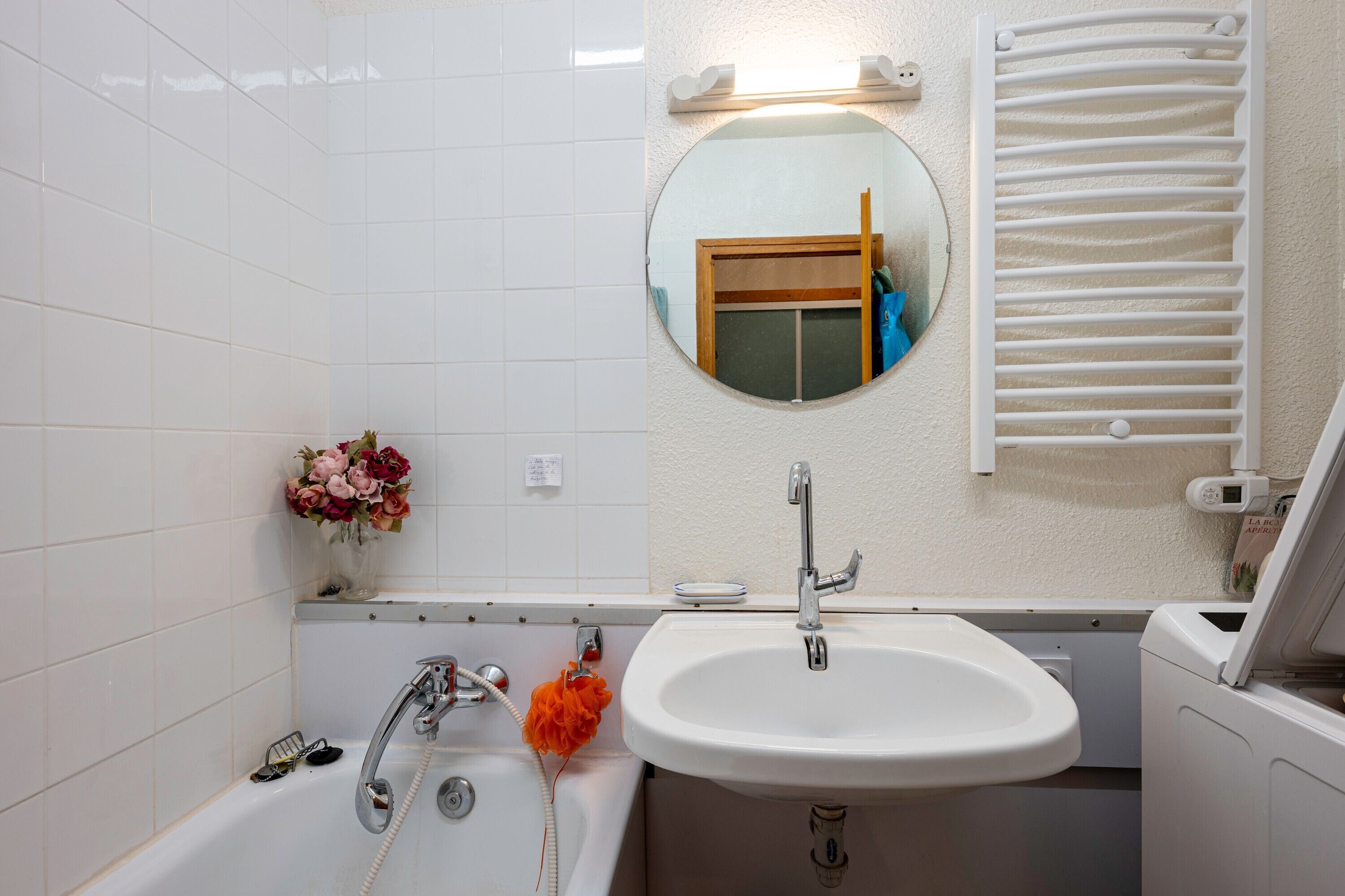 Une salle de bain avec une baignoire, un lavabo, un miroir et un porte-serviettes.