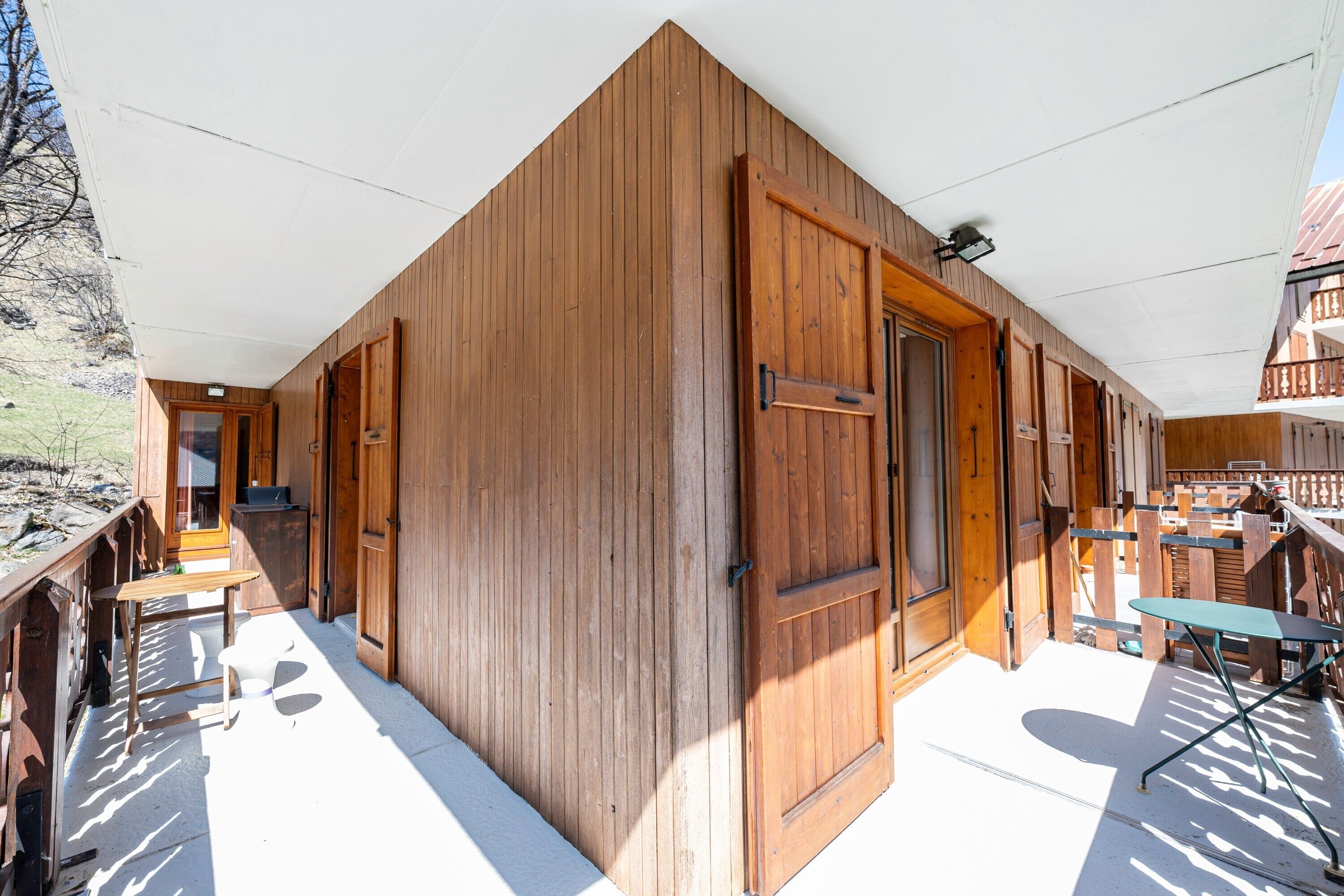 Un edificio de madera con balcón, puerta y una mesa.