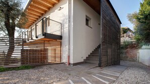 A modern house with a wooden staircase, a balcony, and a gravel driveway. - Studio 'Pai 521 Open Space' with Lake View, Wi-Fi and Air Conditioning (Torri del Benaco)