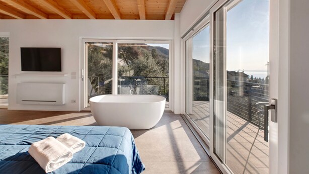 A modern bedroom with a large bed, a bathtub, and a TV. - Studio 'Pai 521 Open Space' with Lake View, Wi-Fi and Air Conditioning (Torri del Benaco)