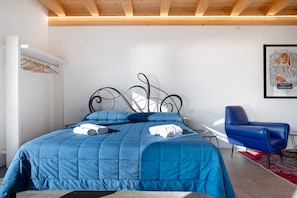 Een slaapkamer met een bed, een stoel en een kunstwerk aan de muur.