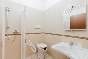Un baño con ducha, inodoro, lavabo y espejo.