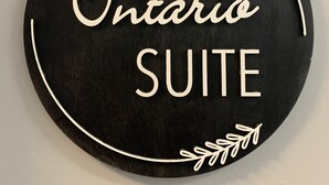 En rund skylt med texten ”Ontario SUITE” omgiven av dekorativa bladmotiv.
