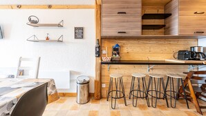 Une cuisine avec des meubles de rangement en bois, un plan de travail noir et des tabourets de bar.
