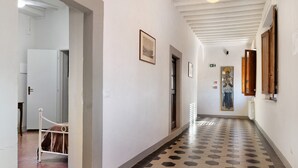 Un pasillo con piso de baldosas, una cama en la esquina izquierda y una puerta que da a otra habitación.