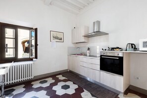 A kitchen with a window, white cabinets, a stove, and a radiator. - Room 'Doppia' with Wi-Fi (San Miniato)
