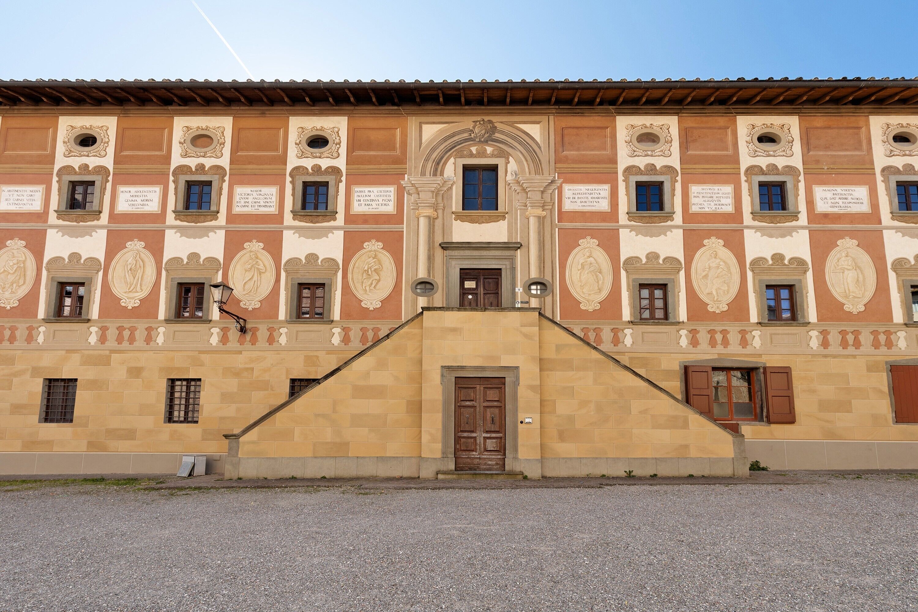 Un bâtiment à la façade symétrique, doté de nombreuses fenêtres et d’une entrée centrale avec une porte.