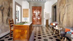 Una habitación con un escritorio de madera, sillas, piso estampado y una puerta grande con diseño decorativo.