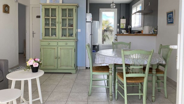 A kitchen with a dining area, featuring a green cabinet, a white table, and chairs.