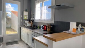 A modern kitchen with white cabinets, a wooden countertop, and a window with a view of the outside.