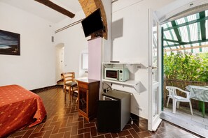 A compact room with a bed, a desk with a computer, a microwave, and a TV. - Room 'Ortensia' with Mountain View, Shared Pool and Wi-Fi (Fontona)