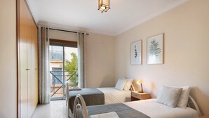 A hotel room with two beds, a balcony, and a view of greenery. - Apartment 'Condomínio Do Vale' with Shared Pool, Shared Terrace and Wi-Fi (Guia)