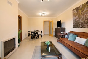 Una sala de estar con chimenea, un sofá, una mesa de centro, un televisor y un comedor con sillas y una mesa.