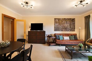 Una sala de estar con un sofá, un televisor, una mesa de comedor y un cuadro en la pared.