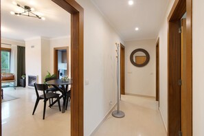 Un intérieur moderne comprenant un coin repas, un couloir et un grand miroir rond accroché au mur.
