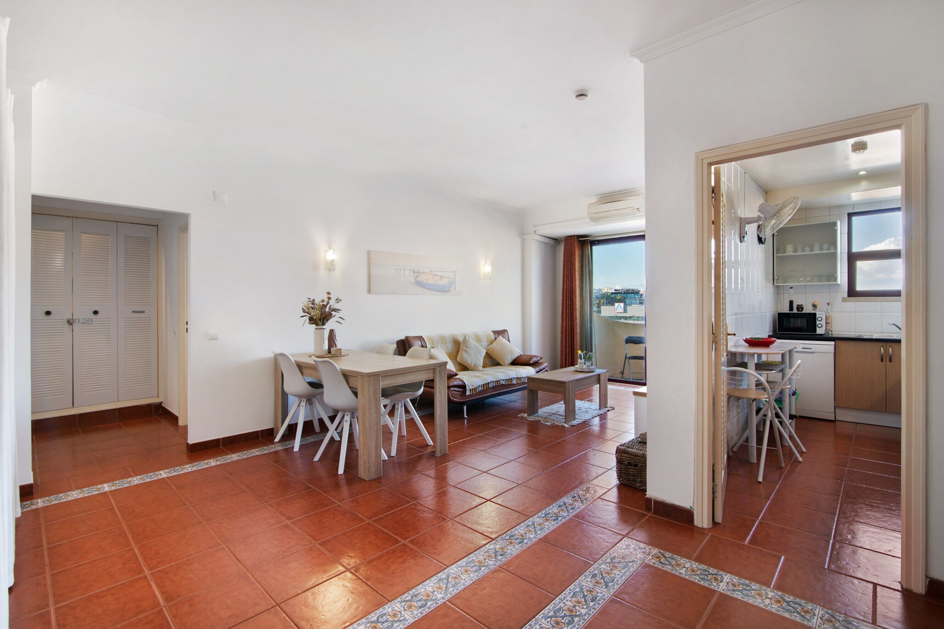 A spacious living area with a dining table, sofa, and kitchen area visible through an open doorway.