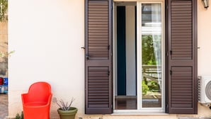 Un bâtiment avec une porte, une plante en pot et une chaise rouge.