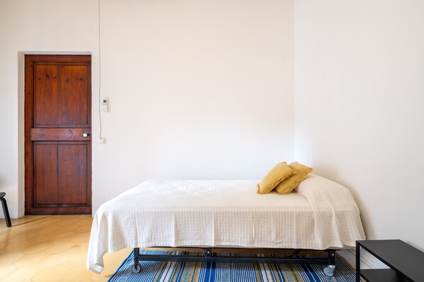 A bedroom with a bed, a wooden door, and a small black table.