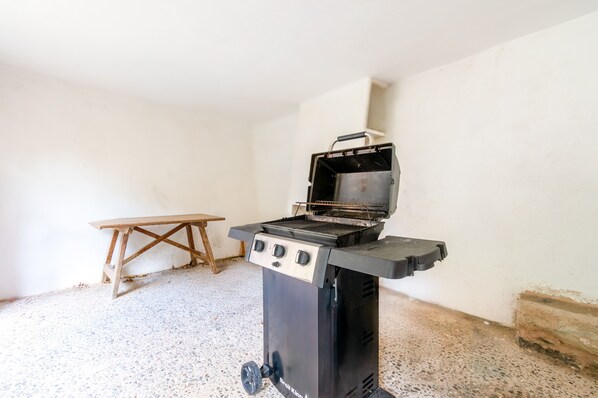A portable grill in a room with a wooden table and a white wall.