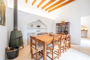 Un comedor con mesa de madera, sillas, estufa y un armario.